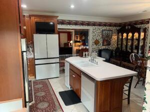 kitchen featuring an island with sink, a kitchen breakfast bar, freestanding refrigerator, light countertops, and dishwasher