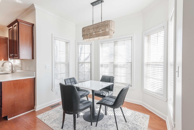 dining area with visible vents, light wood-type flooring, baseboards, and ornamental molding