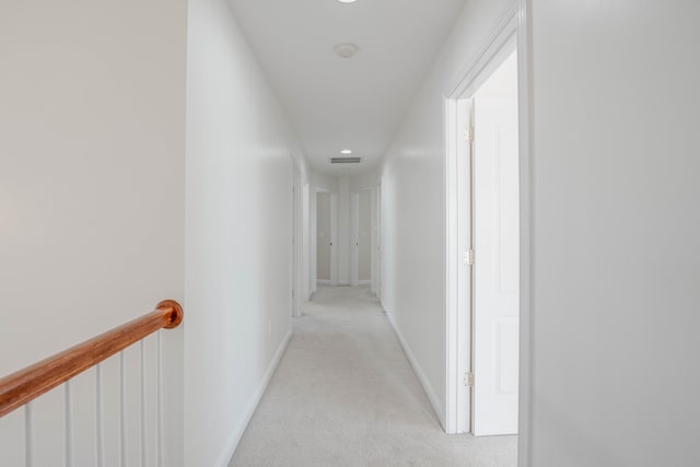 hallway featuring light carpet and baseboards