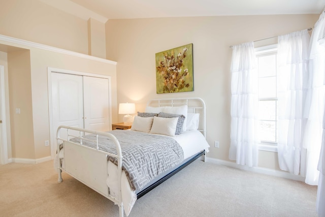 bedroom featuring a closet, baseboards, lofted ceiling, and carpet