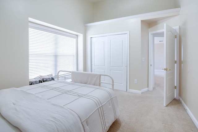 bedroom with baseboards, a closet, and light carpet