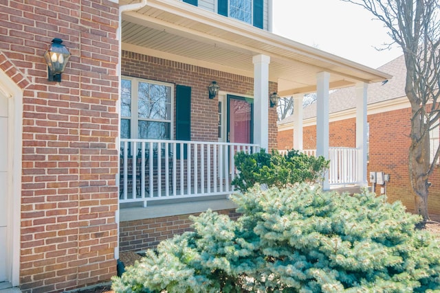 view of exterior entry featuring brick siding and covered porch