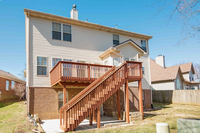 rear view of property featuring brick siding, stairway, a deck, and fence