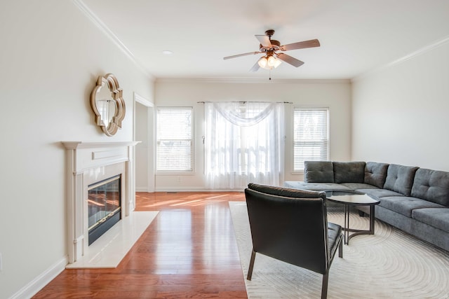 living area featuring a wealth of natural light, a premium fireplace, wood finished floors, and crown molding