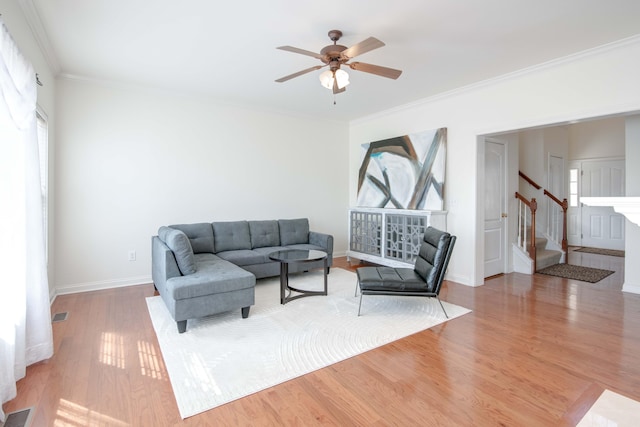 living area with visible vents, wood finished floors, crown molding, baseboards, and stairs