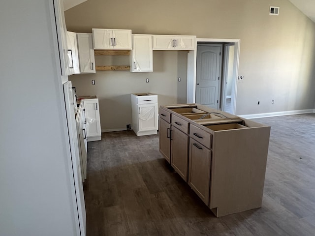 kitchen featuring dark wood-style floors, visible vents, a kitchen island, and lofted ceiling