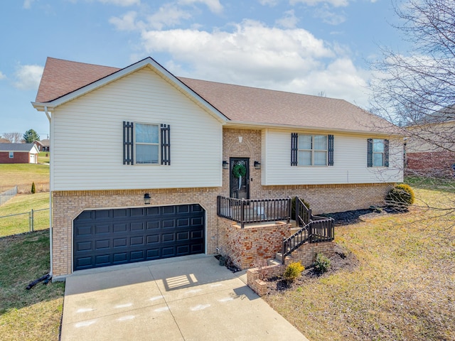 bi-level home featuring fence, an attached garage, concrete driveway, a front lawn, and brick siding