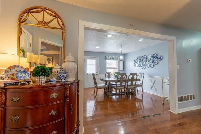 dining room with visible vents, baseboards, a textured ceiling, and wood finished floors