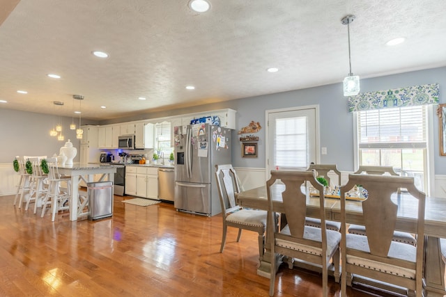 dining space with light wood-style flooring, recessed lighting, and a textured ceiling