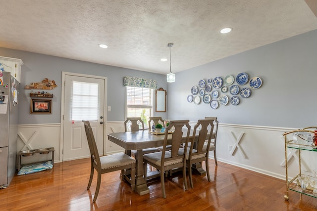 dining space with hardwood / wood-style floors, recessed lighting, a wainscoted wall, and a textured ceiling