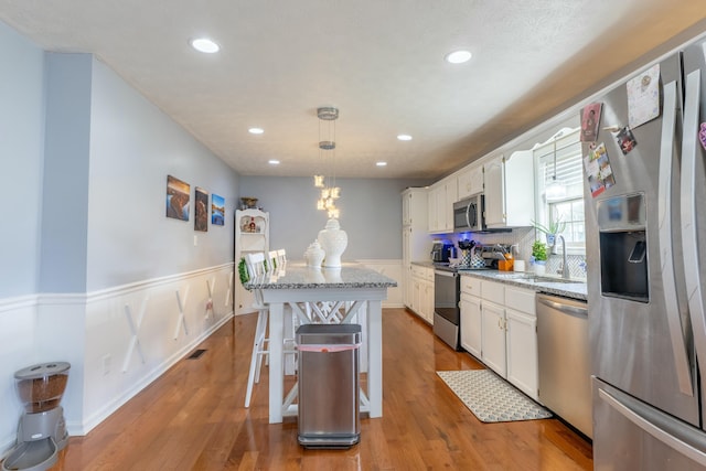 kitchen featuring wainscoting, appliances with stainless steel finishes, white cabinetry, and a sink