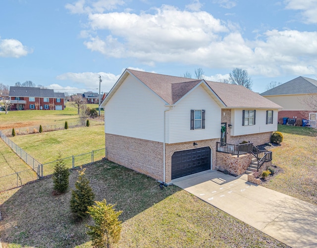 split foyer home with brick siding, a front lawn, fence, concrete driveway, and a garage