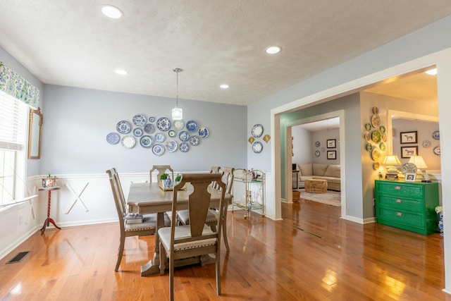 dining room with light wood finished floors, visible vents, and a textured ceiling