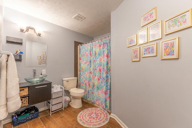 bathroom with vanity, visible vents, wood finish floors, a textured ceiling, and toilet