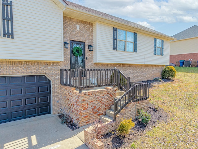 property entrance featuring brick siding, an attached garage, driveway, and a lawn