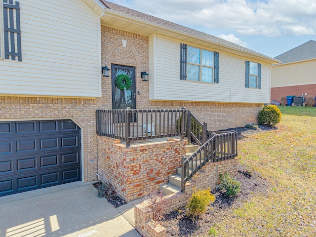 entrance to property with an attached garage, a lawn, brick siding, and driveway