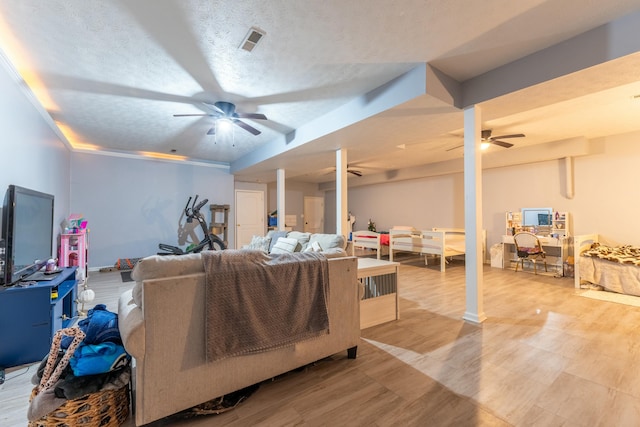 living room featuring visible vents, a textured ceiling, and ceiling fan