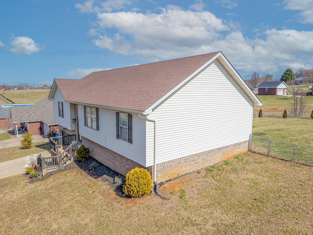 view of property exterior with fence, a lawn, and roof with shingles