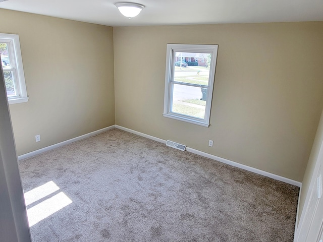 carpeted empty room with visible vents, baseboards, and a healthy amount of sunlight