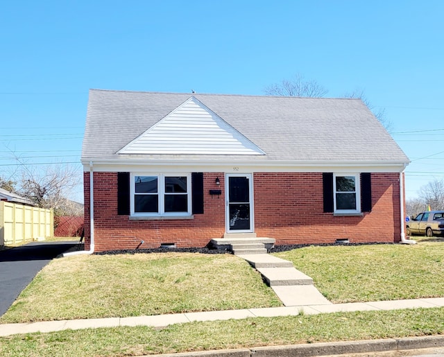 view of front of home featuring brick siding, entry steps, a front yard, and fence