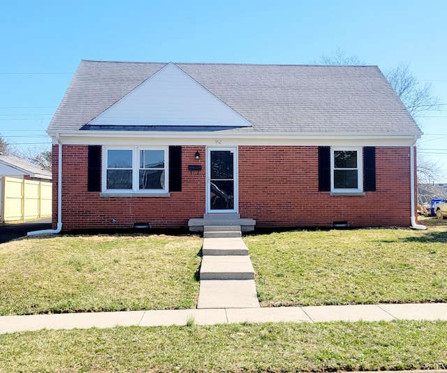 view of front of house with brick siding, entry steps, a front lawn, and roof with shingles