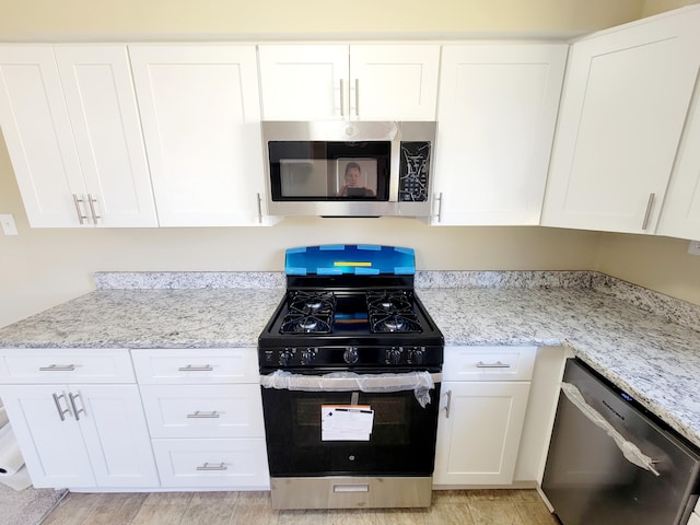 kitchen featuring stainless steel appliances, light stone countertops, and white cabinets