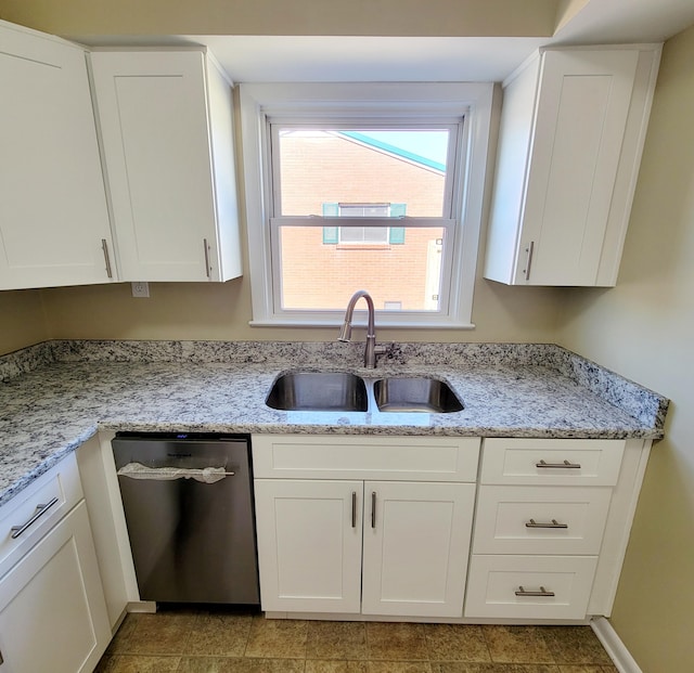 kitchen with stainless steel dishwasher, light stone counters, white cabinetry, and a sink