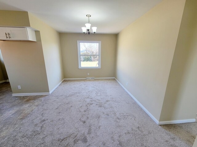 unfurnished dining area featuring visible vents, baseboards, light colored carpet, and an inviting chandelier