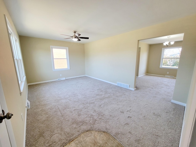 carpeted empty room featuring a wealth of natural light, visible vents, and baseboards