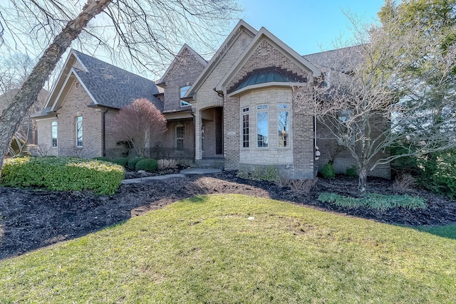 view of front of property with brick siding, roof with shingles, and a front yard