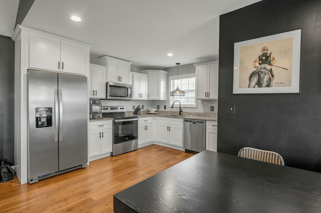 kitchen featuring a sink, stainless steel appliances, white cabinets, and light wood-style flooring