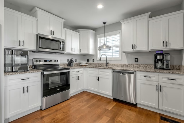 kitchen featuring visible vents, light wood-type flooring, a sink, white cabinetry, and appliances with stainless steel finishes