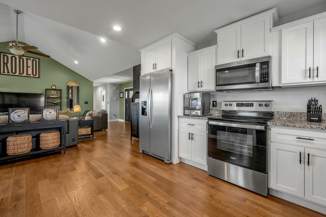 kitchen with light wood-type flooring, a ceiling fan, open floor plan, appliances with stainless steel finishes, and light stone countertops