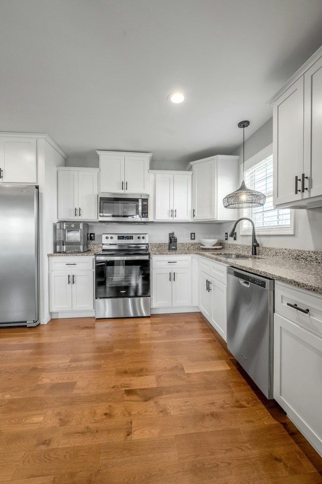 kitchen featuring white cabinetry, light wood-type flooring, appliances with stainless steel finishes, and a sink