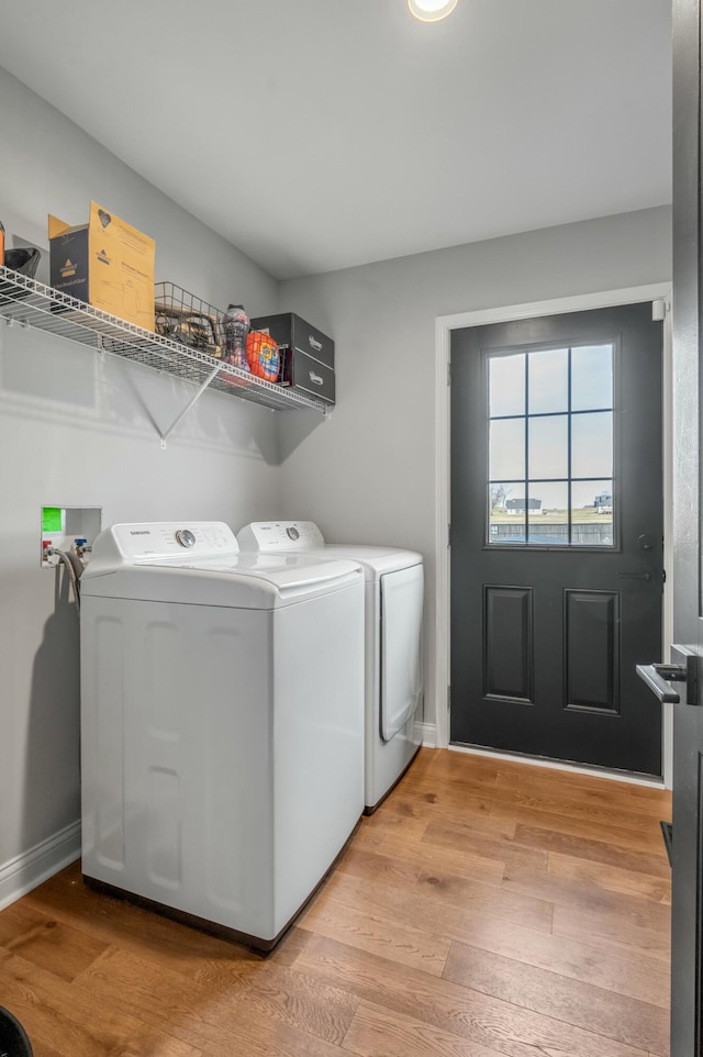 laundry area featuring laundry area, washing machine and dryer, light wood-type flooring, and baseboards