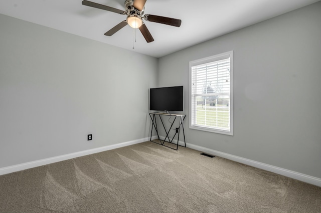 carpeted spare room featuring baseboards, visible vents, and ceiling fan