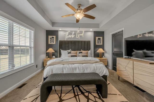 bedroom featuring visible vents, light colored carpet, a raised ceiling, and baseboards