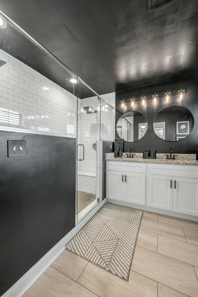 bathroom with double vanity, tile patterned flooring, a shower stall, and a sink