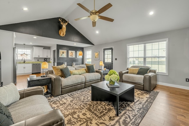 living room featuring light wood finished floors, baseboards, ceiling fan, recessed lighting, and high vaulted ceiling