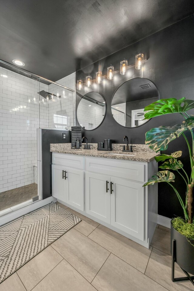 bathroom featuring double vanity, tile patterned flooring, a shower stall, and a sink