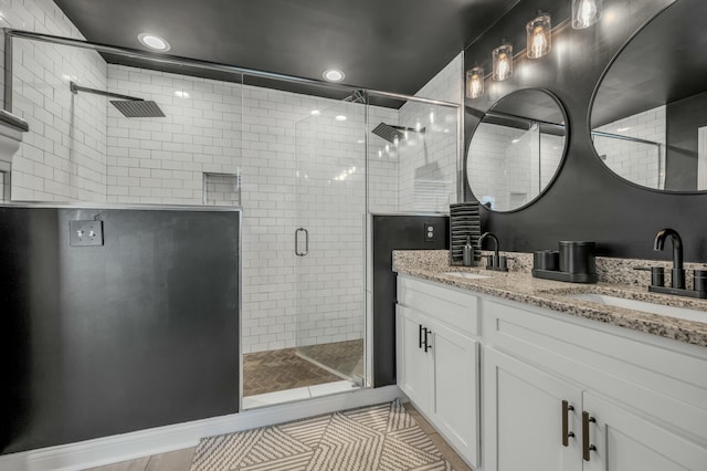 bathroom featuring a sink, a stall shower, and double vanity