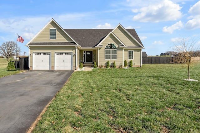 view of front of property featuring a front yard, fence, driveway, roof with shingles, and a garage