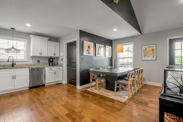 kitchen featuring light stone countertops, white cabinetry, light wood finished floors, a sink, and dishwasher