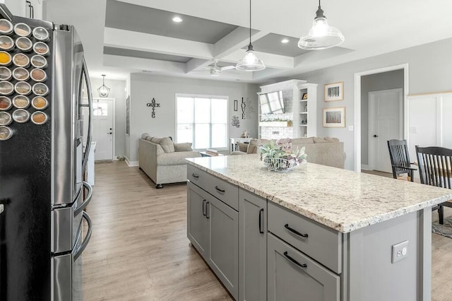 kitchen featuring coffered ceiling, light wood-style flooring, freestanding refrigerator, gray cabinetry, and open floor plan