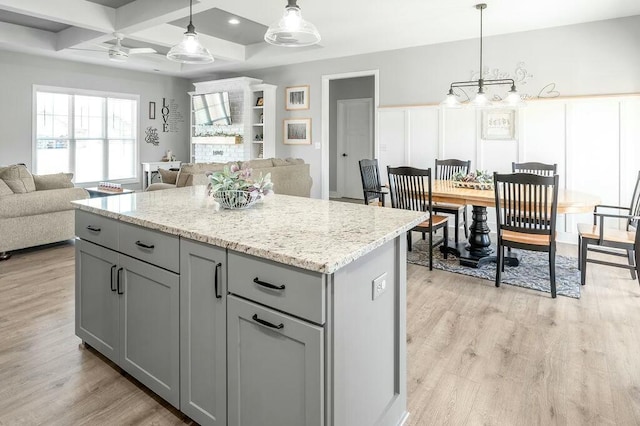 kitchen featuring open floor plan, pendant lighting, gray cabinets, light wood-style floors, and coffered ceiling