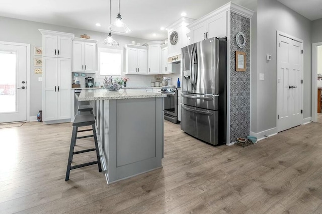 kitchen with white cabinets, backsplash, appliances with stainless steel finishes, and a center island