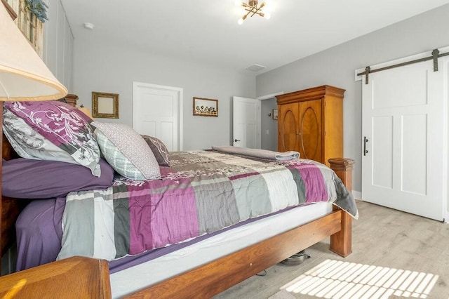 bedroom featuring a barn door and wood finished floors