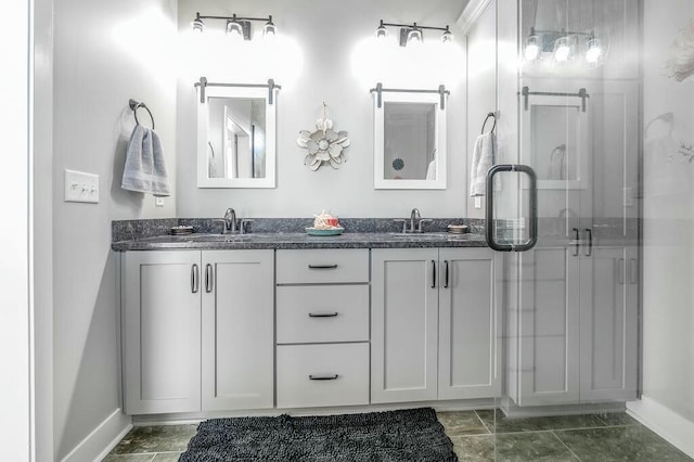 bathroom with a sink, a stall shower, baseboards, and double vanity