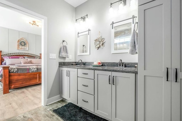 ensuite bathroom featuring a sink, baseboards, ensuite bath, and double vanity