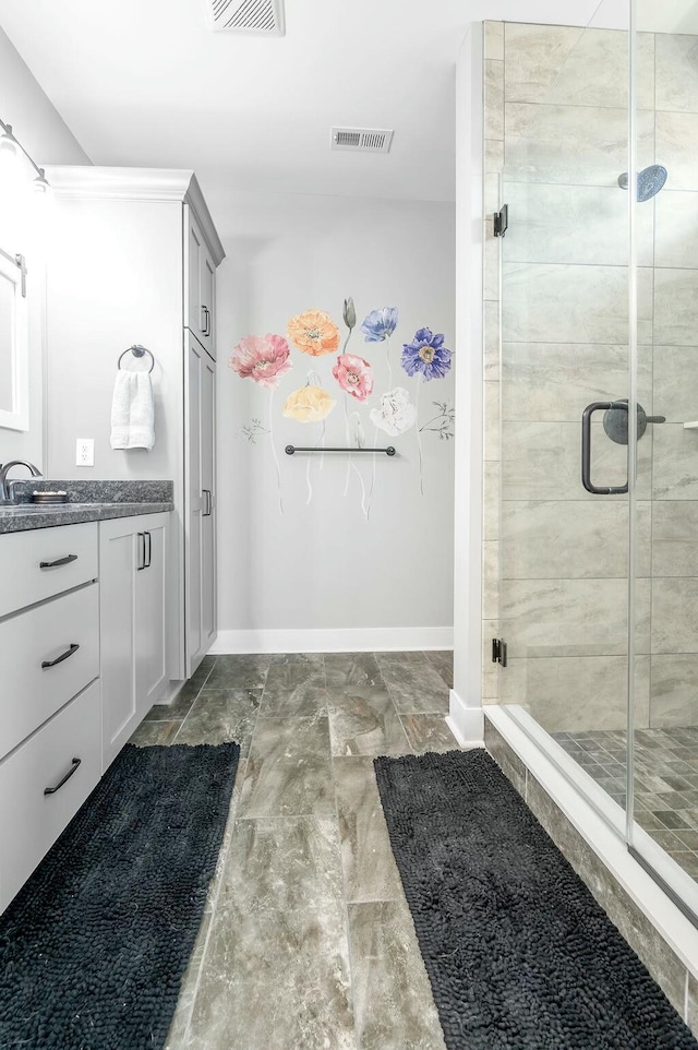 full bath featuring visible vents, baseboards, vanity, and a shower stall